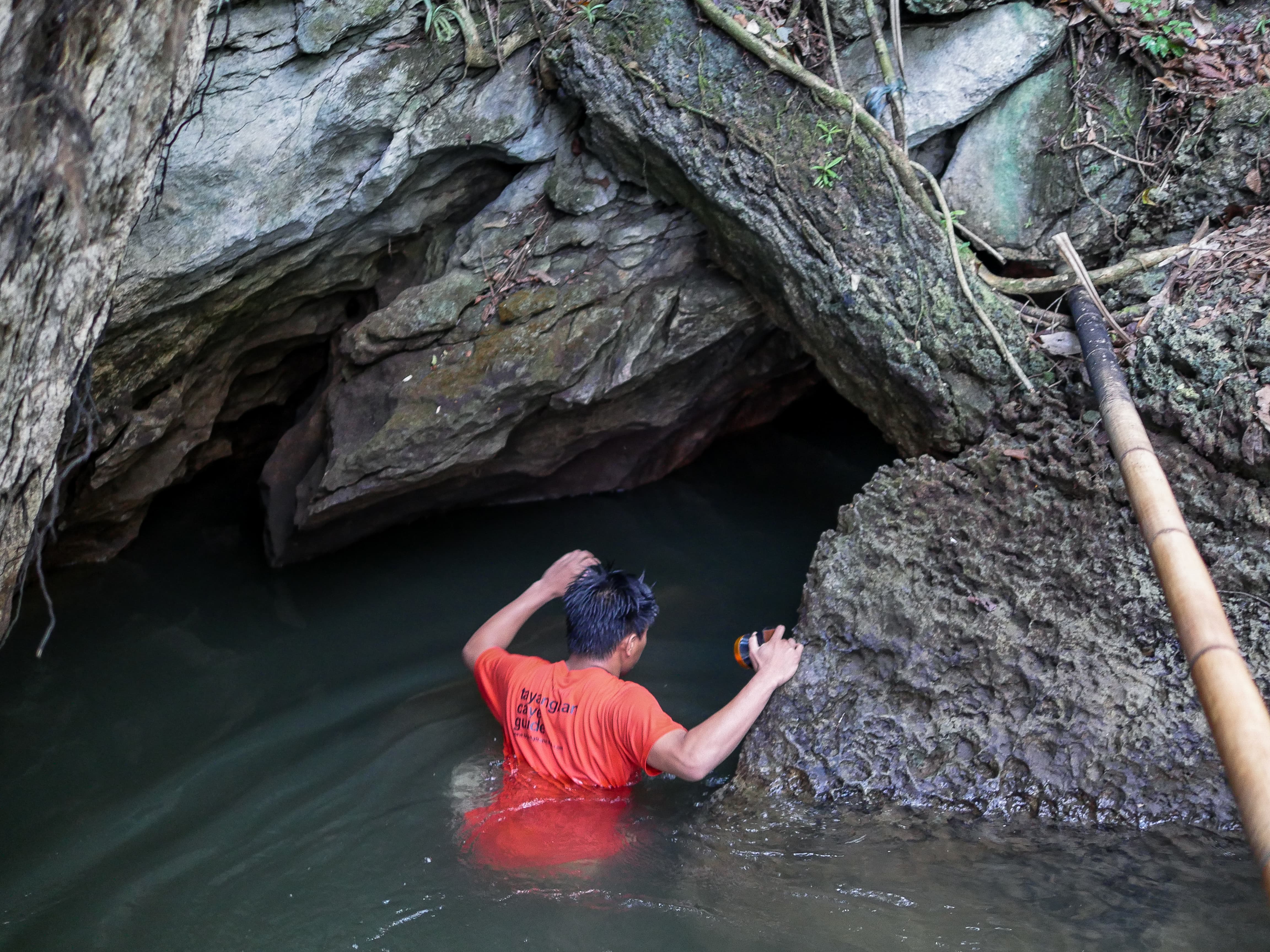 guide leading visitor towards entrance of tayangban cave in siargao philippines